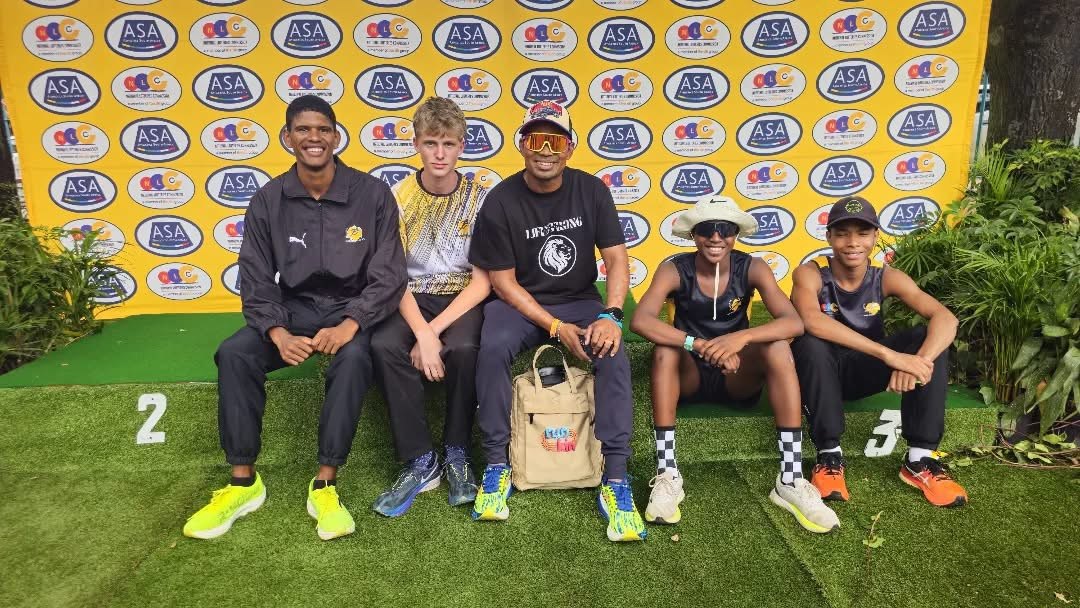 Group of five people seated in front of a branded backdrop at an athletics event
